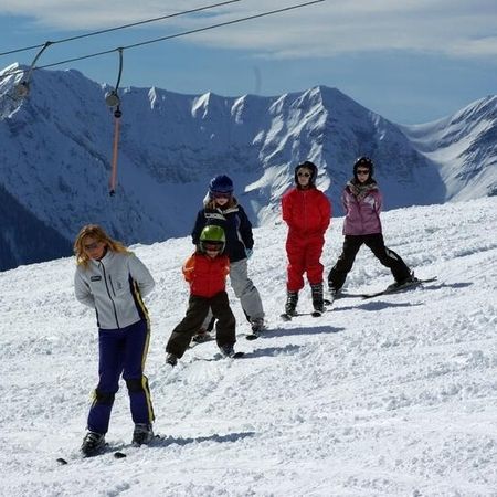 Eine Gruppe von Urlaubern auf einer Skipiste, die fröhlich Ski fahren und die winterliche Landschaft genießen.
