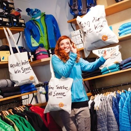 Eine Frau steht in einem Laden und trägt eine Tüte mit Kleidung in der Hand.