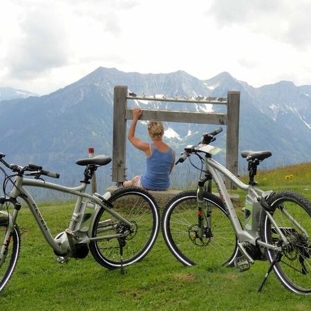 Eine Urlauberin genießt den Ausblick auf dem Berg während Ihrer Fahrradtour