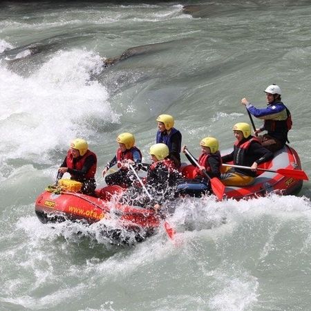 Five people in a raft enjoy whitewater rafting on a lively river.